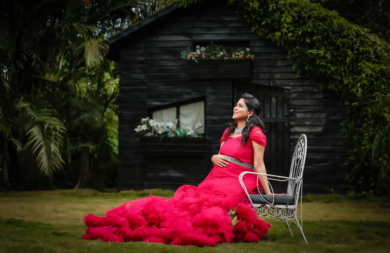 maternity photoshoot sitting on chair pose in pink gown